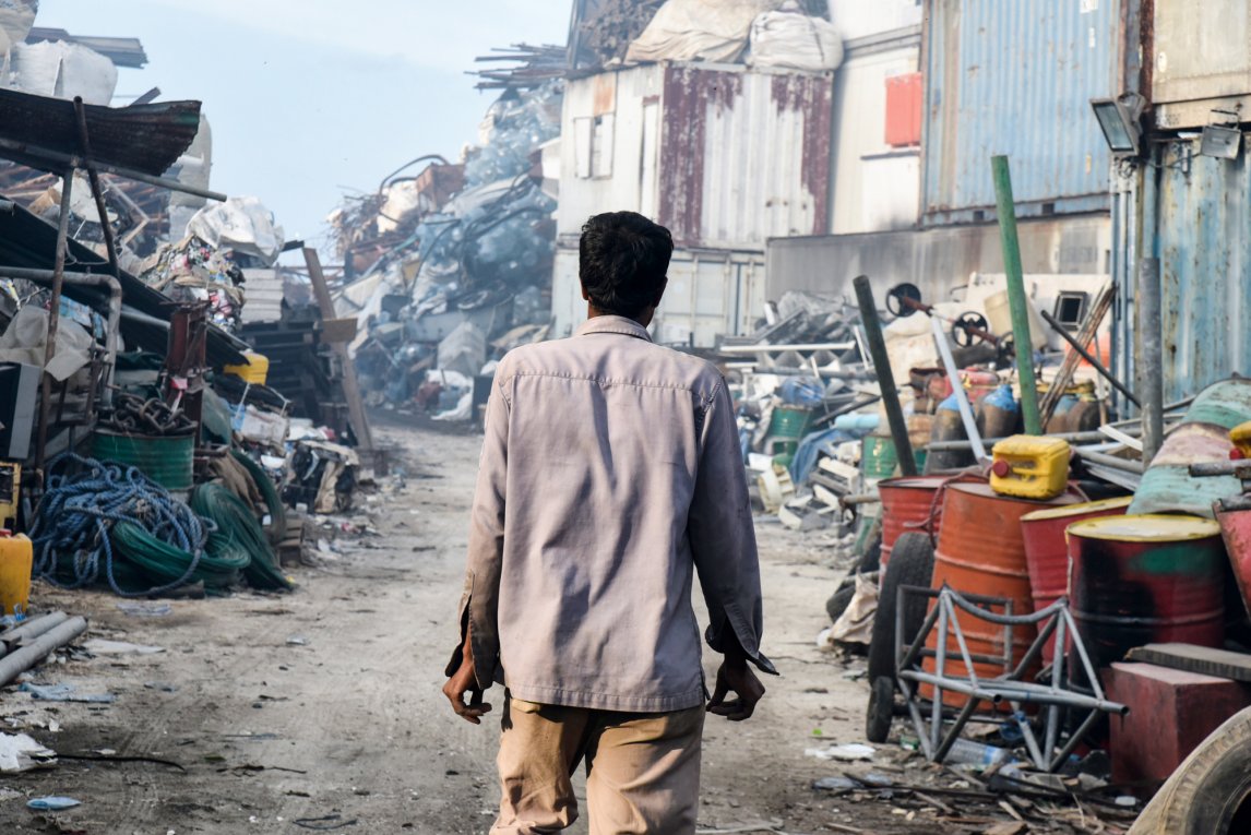 Ein Arbeiter durchstreift die Gänge der Müllkippe auf Thilafushi. Rechts in den Containern lagern die aussortierten Altmetalle, die regelmäßig nach Indien verschifft werden
