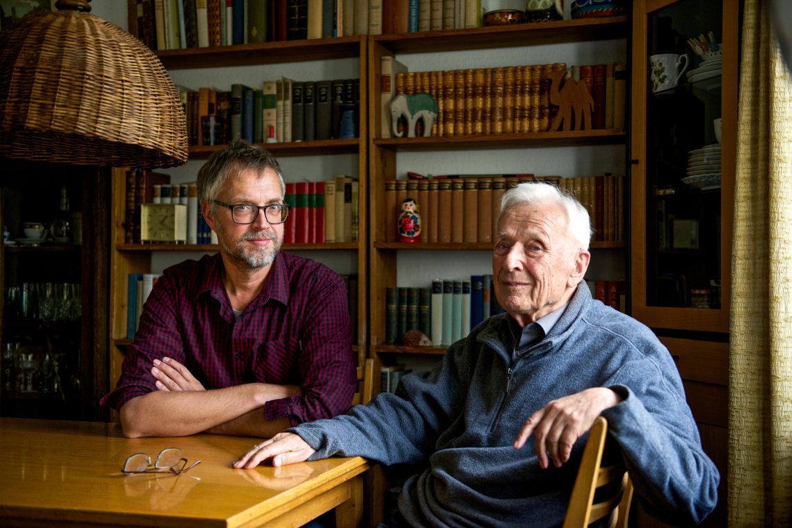 Friedrich Hassenstein und sein Sohn Wolfgang Hassenstein, sitzend am Esstisch vor einer Regalwand voller Bücher.