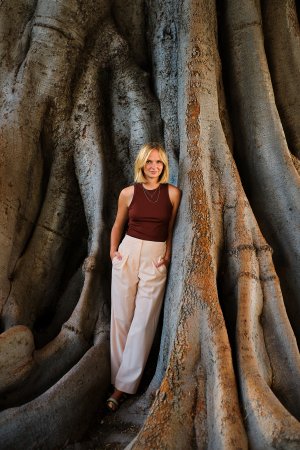 Autorin Kristina Lunz steht zwischen den Wurzeln eines großen Baumes